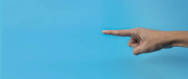 stock image A woman's hand with an index finger on a blue background. Copy space. Banner.