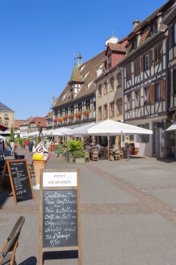 Obernai, Fransa - 11 Ağustos 2022: Obernai 'deki Rue du Marche caddesinde restoranları ve tarihi binaları olan eski bir kasaba. Fransa 'nın Alsace bölgesindeki Bas-Rhin departmanı