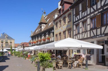Obernai, Fransa - 11 Ağustos 2022: Obernai 'deki Rue du Marche caddesinde restoranları ve tarihi binaları olan eski bir kasaba. Fransa 'nın Alsace bölgesindeki Bas-Rhin departmanı