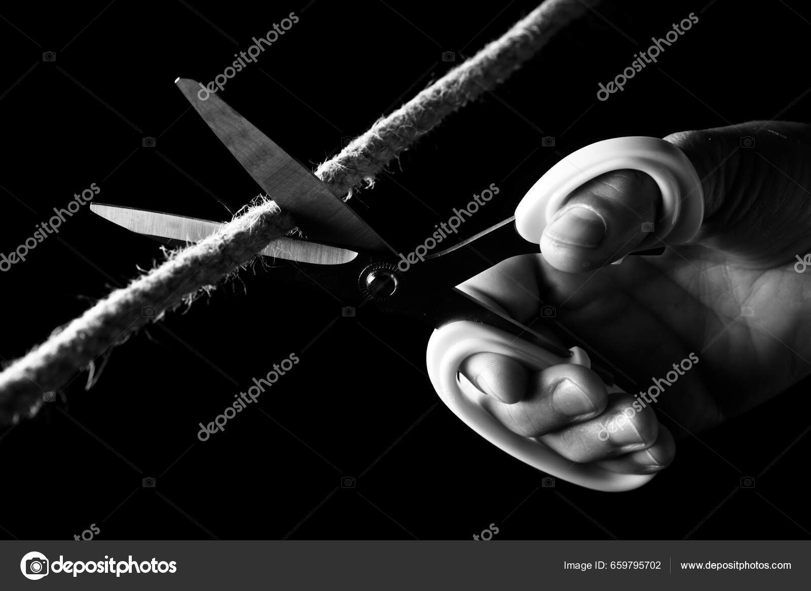 Cutting A Rope With Scissors Against White Background Stock Photo