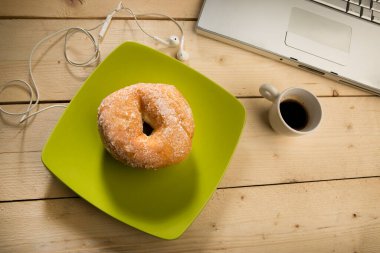 Çörek tabakta, kahve fincanı da tahta masada.
