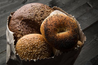 Tahta bir masada izole edilmiş, kağıt bir torbanın içindeki çeşitli karakteristik ve tipik ekmek türleri.