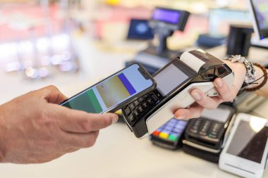 Ödemenin ayrıntıları bir satıcının elinde tuttuğu pozisyonlara doğru akıllı telefonlu bir kredi kartıyla.