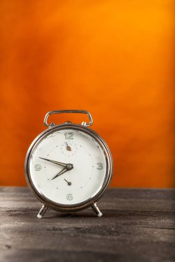 Kaliteli yuvarlak saat ahşap masa ve turuncu arka plan