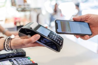Ödemenin ayrıntıları bir satıcının elinde tuttuğu pozisyonlara doğru akıllı telefonlu bir kredi kartıyla.