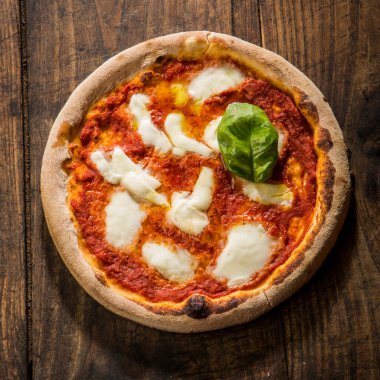 Pizza margherita yukarıdan kesilmiş, ahşap bir masada izole edilmiş.