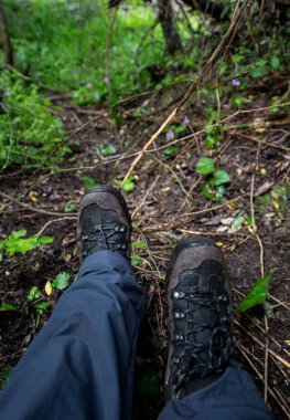 Kırsalda çamurda yürüyen bir adamın yürüyüş botlarının ayrıntıları.