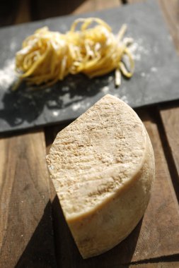 Tahta bir masanın üzerinde çiğ peynir ve makarna.
