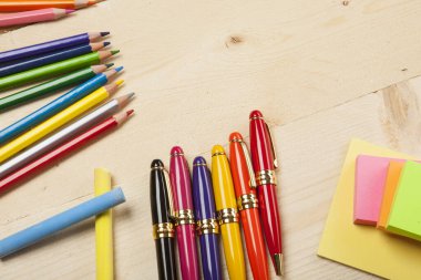 Ahşap masa üstünde renkli kalemler ve kalemler