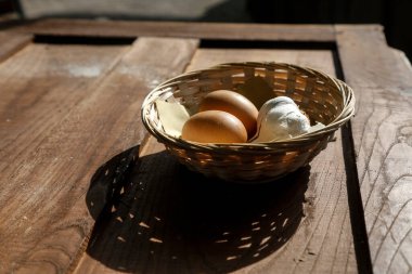 Tahta bir masada duran bir sepet yumurta ve sarımsak.