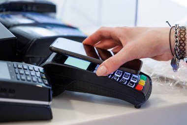 Ödemenin ayrıntıları bir satıcının elinde tuttuğu pozisyonlara doğru akıllı telefonlu bir kredi kartıyla.