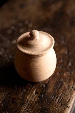 Ahşap masanın üzerinde kapağı olan terracotta kabı.