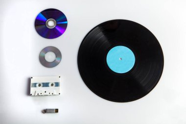 Beyaz arka planda izole edilmiş kasetler, dvd 'ler, kalem sürücüleri gibi farklı çağlardan gelen çeşitli dijital medyalar ile vinil kayıt