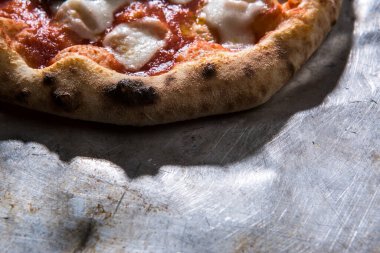 Metal levhada domatesli yuvarlak pizza.