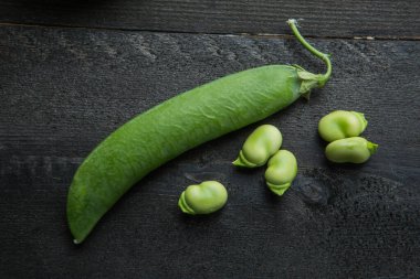 Geniş fasulyeler koyu bir tahta masada izole edilmiş.