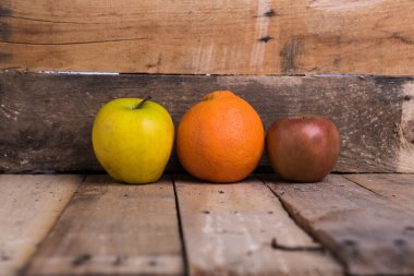 Tahta bir masanın üzerinde taze elma ve portakallar ve metin için yer var. 