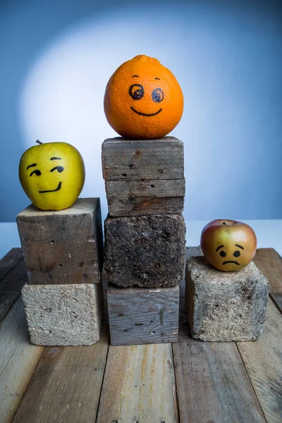 Три Фрукта Нарисованными Улыбающимися Лицами Выражающими Различные Эмоции Помещенные Деревянном — стоковое фото
