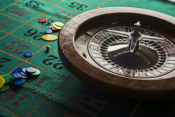 Wooden roulette wheel isolated over a green gaming table with colorful chips