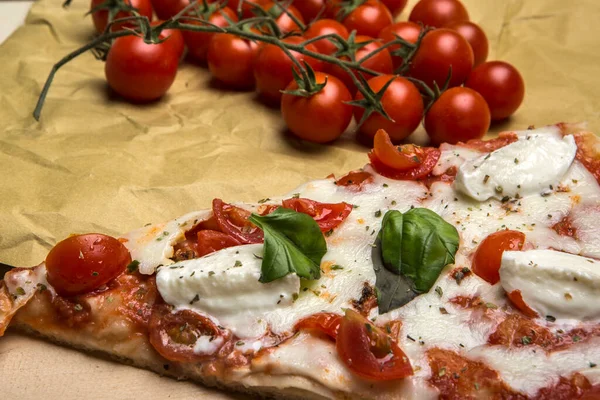 stock image Detail of a wedge of Pizza with tomato and mozzarella on a wooden table