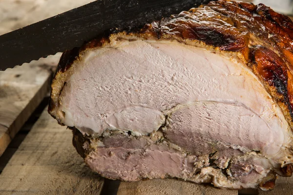 stock image Hand with a yellow knife cuts a slice of roast beef placed on a table