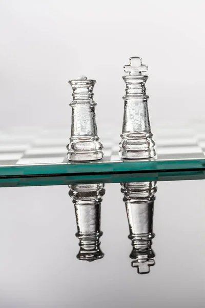 棋盘上的玻璃象棋反射在深色的表面上 — 图库照片