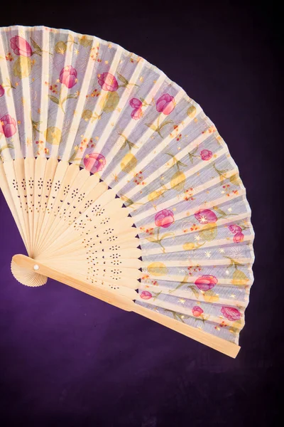 Fan with floral designs on a dark purple background
