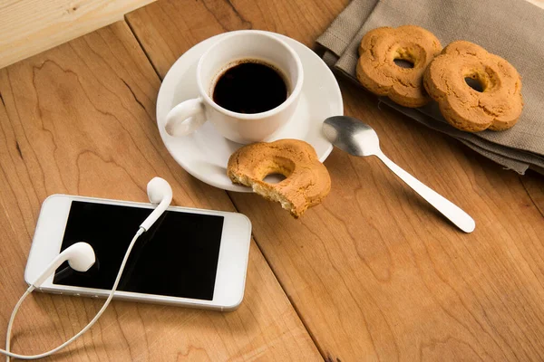 木桌上有饼干和智能手机的咖啡 — 图库照片