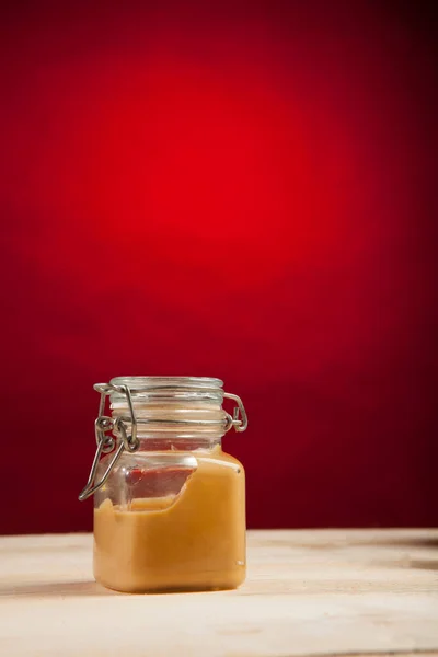Vaso Vetro Con Crema Tavolo Legno Isolato Fondo Rosso — Foto Stock