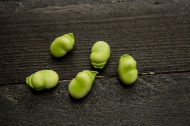 Geniş fasulyeler koyu bir tahta masada izole edilmiş.