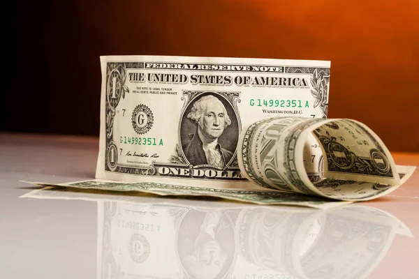 Kahverengi arka planda yuvarlanmış dolar banknotları.