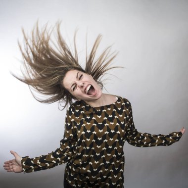 Kahverengi dalgalı saçlı ve beyaz kazaklı kadın kahvesini beyaz arka planda izole edilmiş bir bardaktan içer.