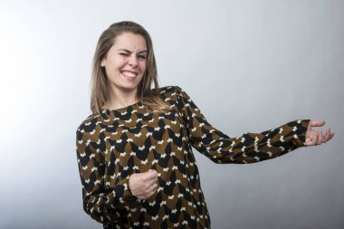 Süveter giyen komik kız dans ediyor ve beyaz arka planda izole edilmiş bir müzik aleti çalıyormuş gibi yapıyor.