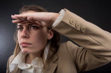 Bej ceketli sarışın menajer siyah arka planda izole bir şekilde elini alnının üstüne koyar.