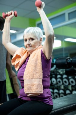 Son sınıf öğrencisi kadın spor salonunda halterlerle fiziksel egzersiz yapıyor.