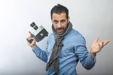 Sakallı ve bıyıklı bir adam klasik kamera tutuyor. 