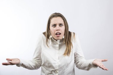 Beyaz tişörtlü sarışın kız beyaz arka planda soyutlanmış bir şekilde şaşkınlığını göstermek için yüzünü buruşturuyor.