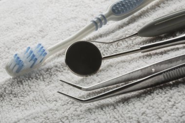 beyaz bir havlunun üzerine yerleştirilmiş çeşitli dişçi aletleri