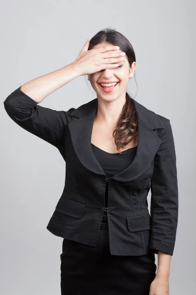white girl with dark hair dressed in black brings her hands over her eyes as a sign of not wanting to see, isolated on gray background
