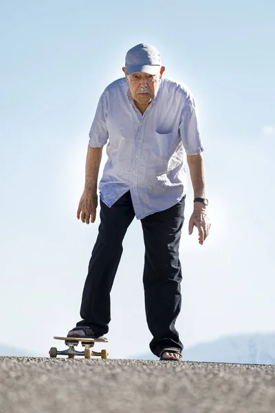 八十岁的老人喜欢在乡间路上滑板 — 图库照片
