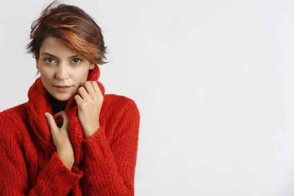 赤いセーターの美しい女の子ボブの髪は寒さのために自分自身をカバーします 赤の背景に隔離 — ストック写真
