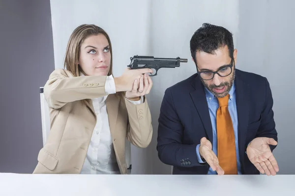这位无聊的秘书坐在办公室里 两个同事用枪指着她说话的老板 — 图库照片