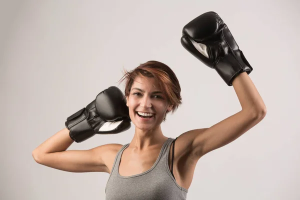 beautiful girl with bob hair and boxing gloves holds gurdia high, isolated on white background