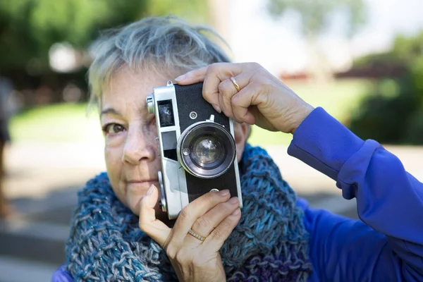 Kıdemli kadın fotoğrafçı kamerayla fotoğraf çekiyor.