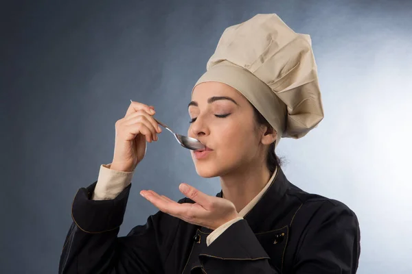 Mujer Chef Prueba Plato Una Cuchara Aislado Sobre Fondo Gris — Foto de Stock