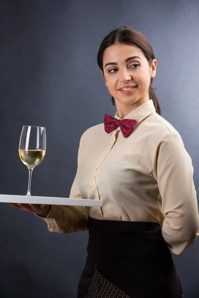 漂亮优雅的女服务员 身穿衬衫 打着红色领结 随时准备为顾客提供一杯酒水 酒水背景是黑色的 — 图库照片