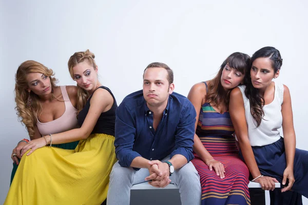 A guy in the middle of 4 seated girls is offended and aloof - white background