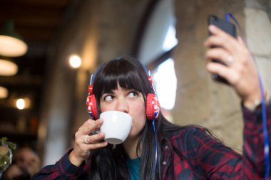 Kafede kulaklıkla müzik dinleyen güzel esmer bir kadının portresi.