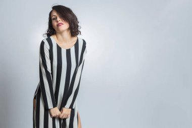 Siyah saçlı, çizgili tişörtlü, gri arka planda soyutlanmış beyaz bir kız.