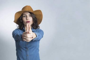 Siyah saçlı, kot gömlekli ve kahverengi şapkalı beyaz bir manken.