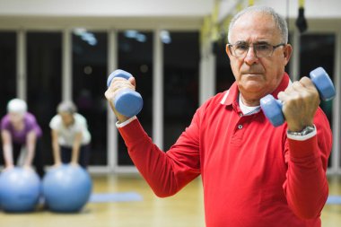Son sınıf öğrencisi kadın spor salonunda dambıllarla egzersiz yapıyor.